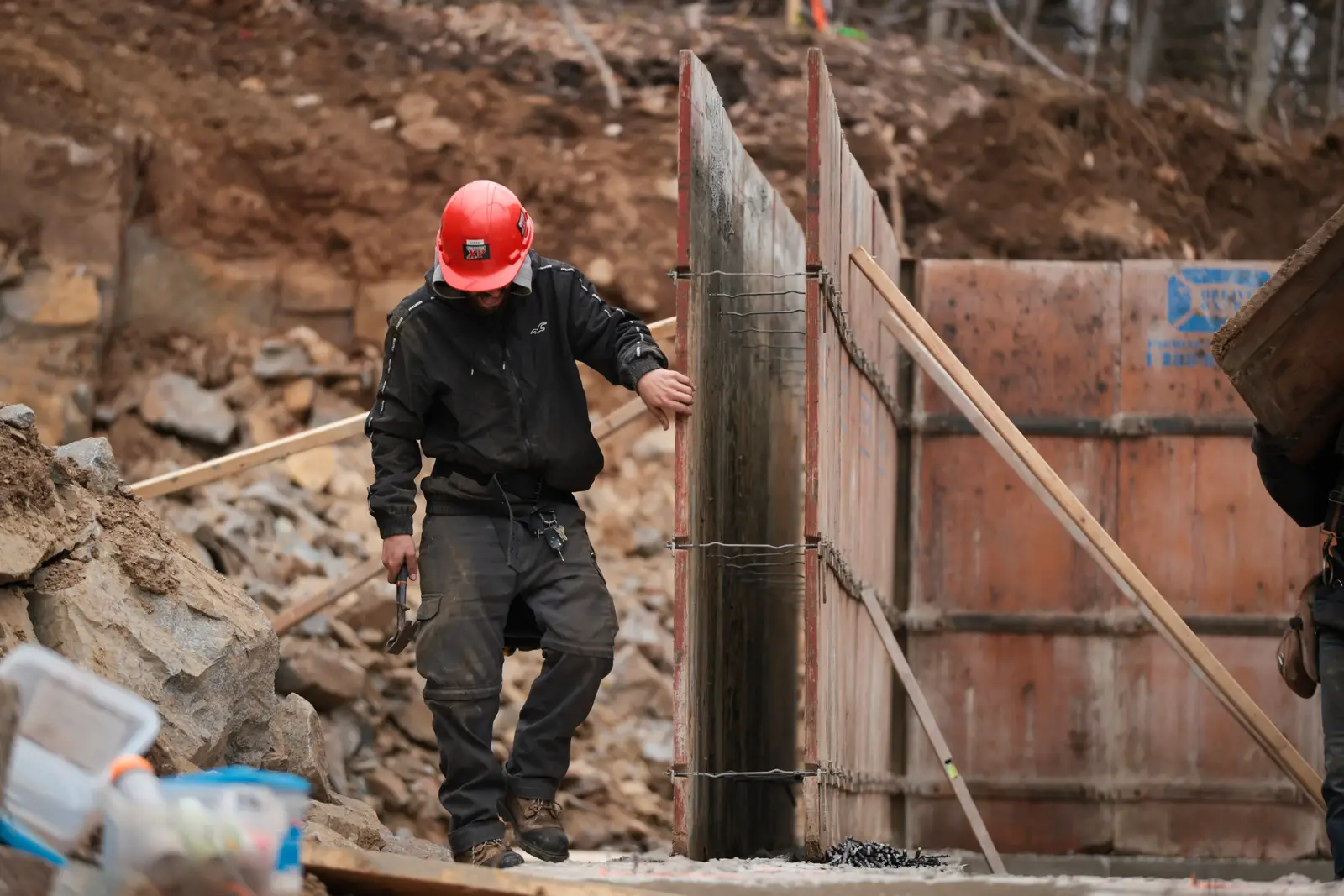 Travailleur ajustant un panneau de coffrage dans une excavation.