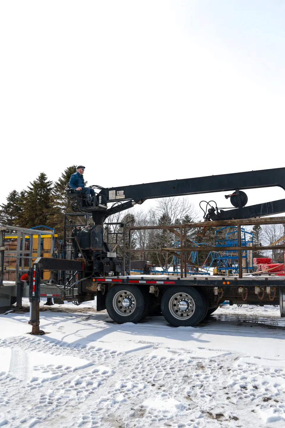Crane truck loaded with forming panels, parked on snow-covered ground.