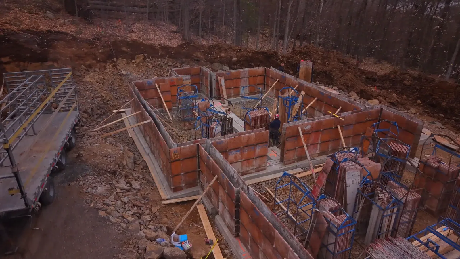 Drone view of a complete foundation: formwork walls up on the footing, a worker at the center of the site.