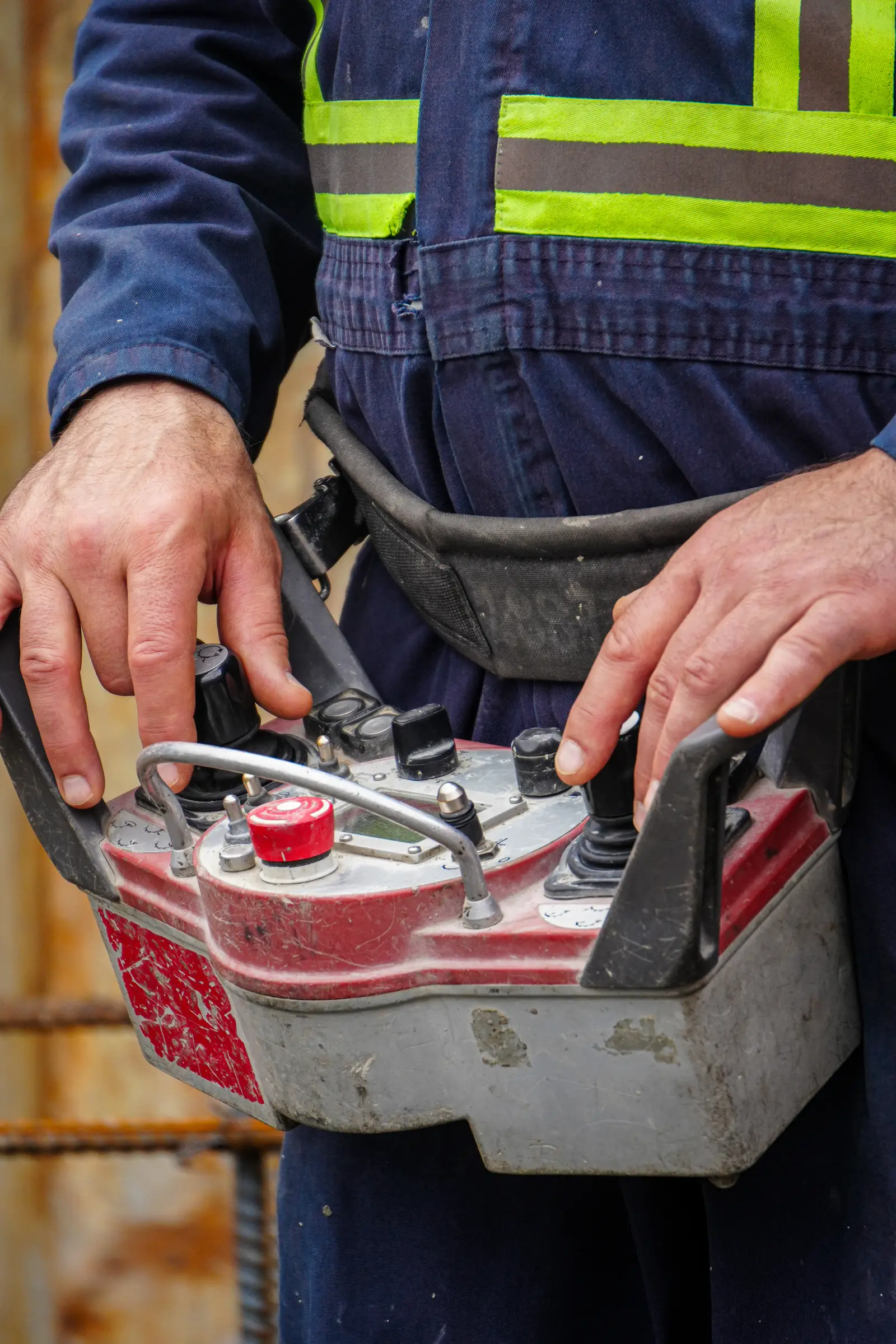 A worker's hands on the remote control of a concrete pump.