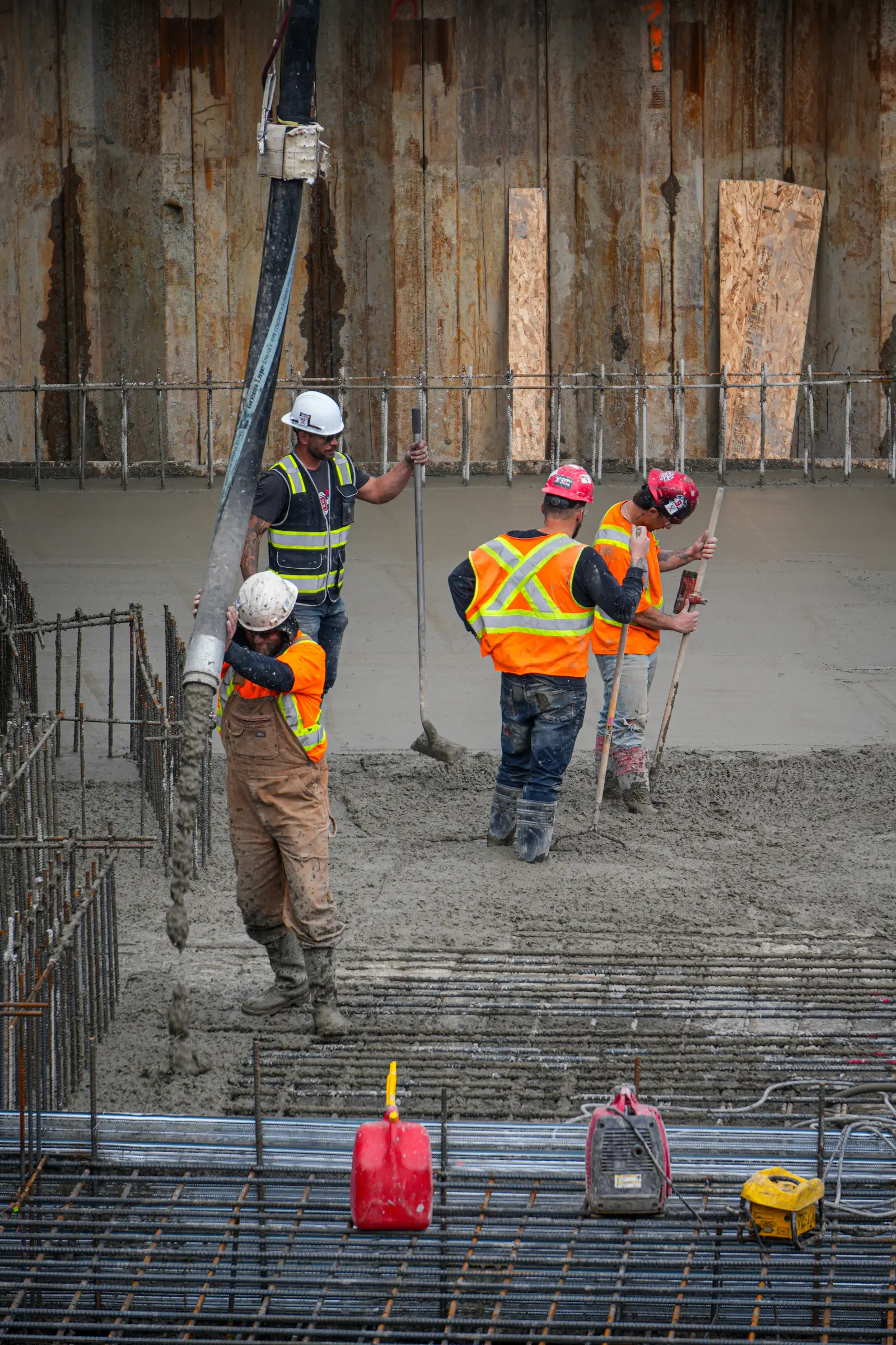 Coulée d'une dalle structurale : cinq travailleurs répartis autour du tuyau de la pompe à béton.