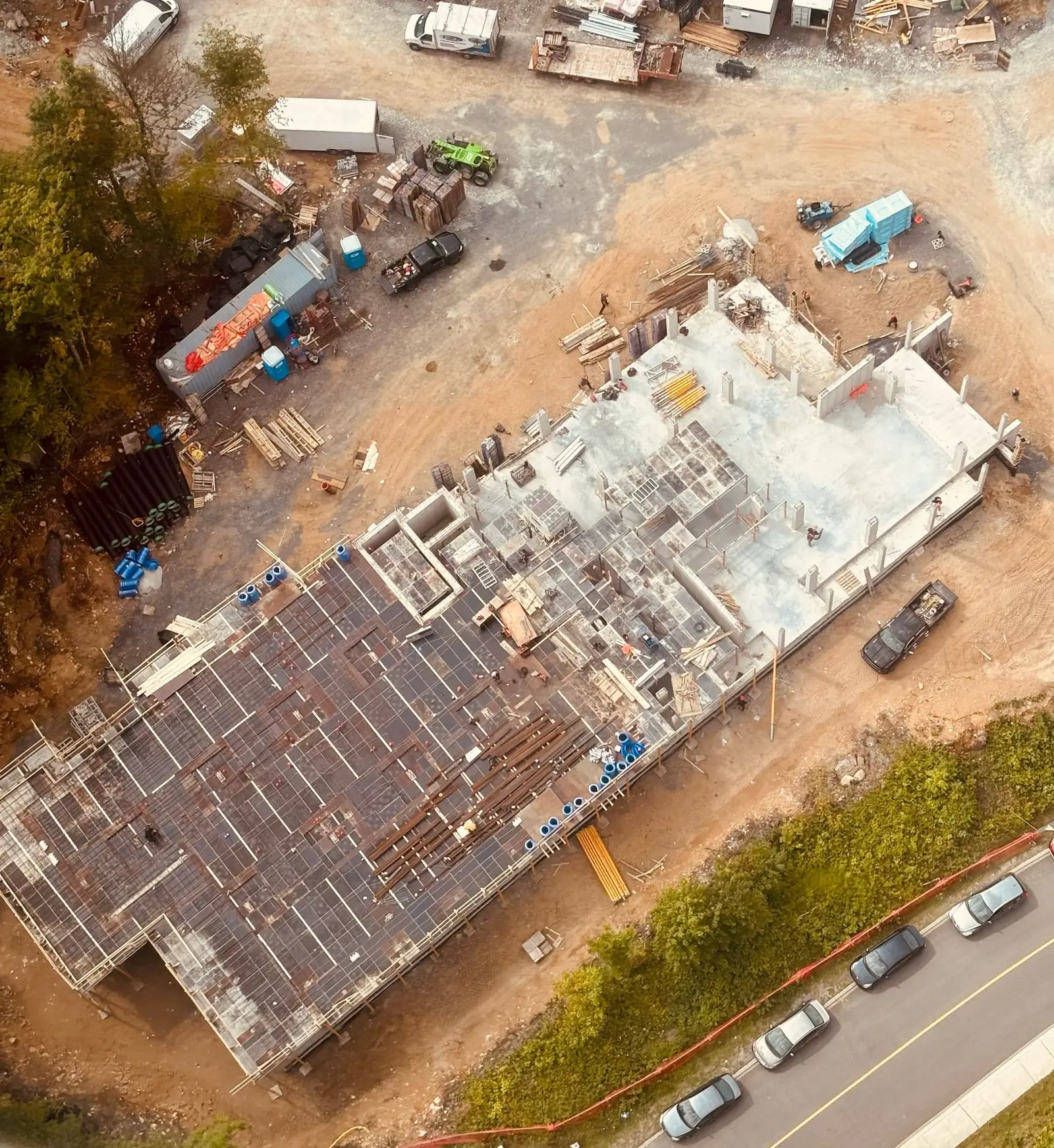 Vue aérienne d'une dalle commerciale coulée, armature et coffrages encore en place sur le pourtour du bâtiment.