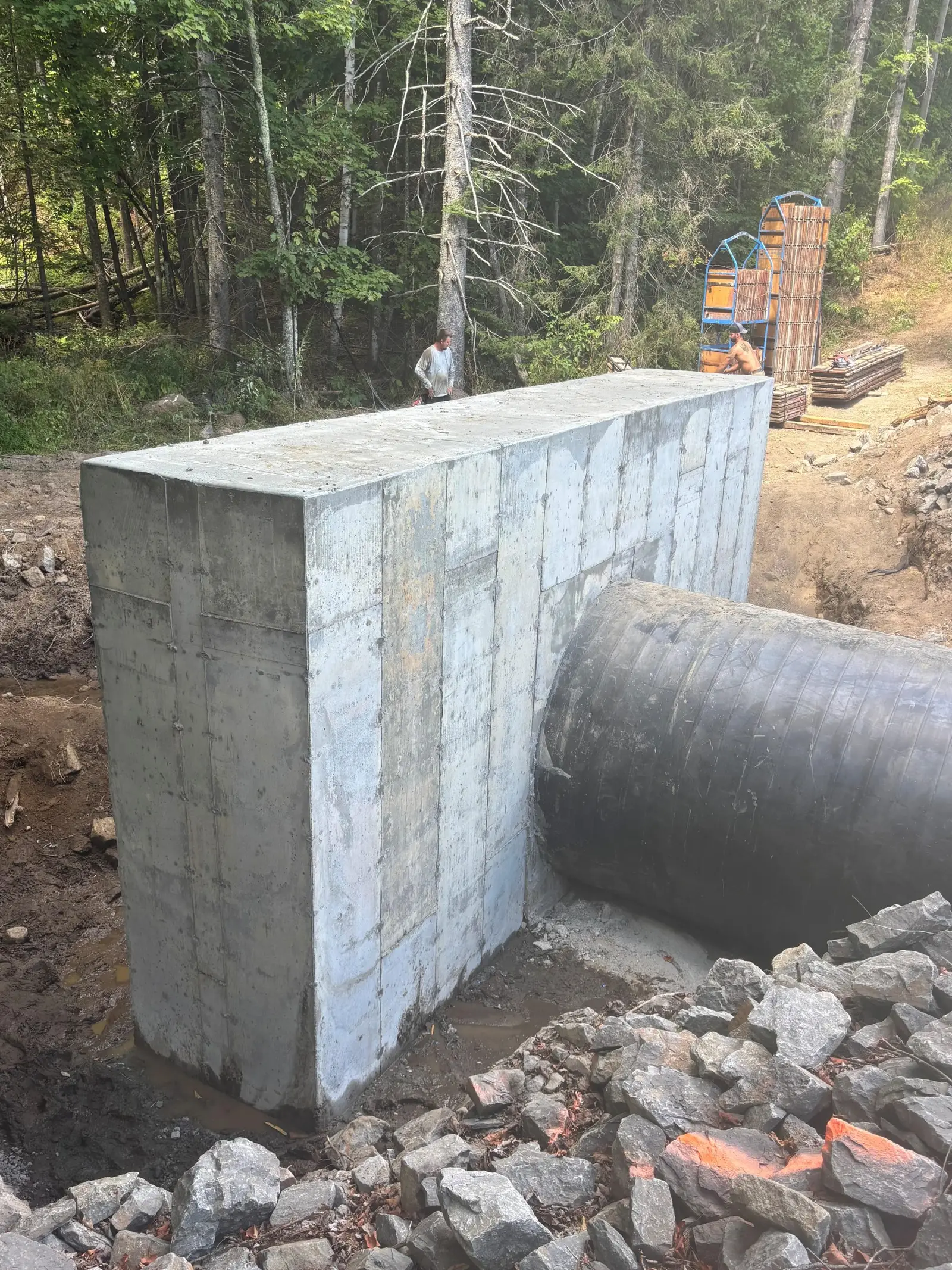 Mur de tête en béton coulé et décoffré à la sortie d'un ponceau, joints de panneaux visibles sur toute la hauteur.